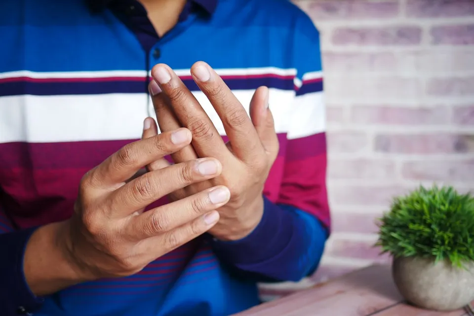 Person massaging their hand, pain caused by finger arthritis